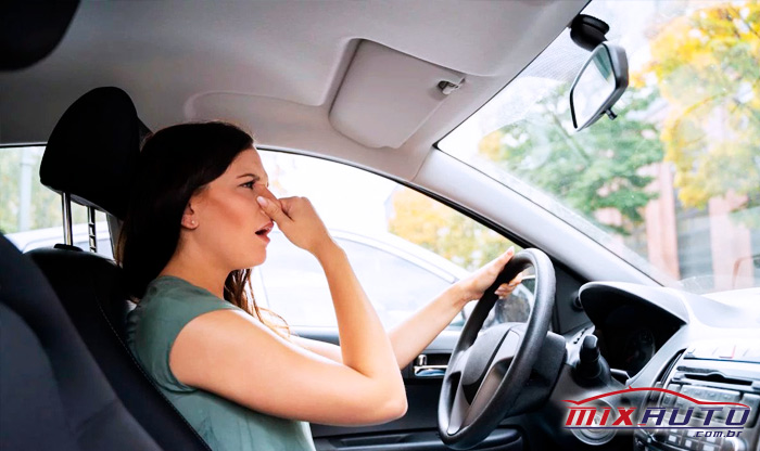 Condutora com uma mão no volante e outra no nariz indica incômodo com o cheiro no interior do carro